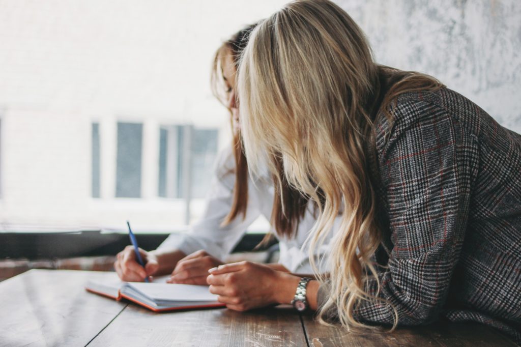 Young successful women colleagues discuss joint project, coaching in loft office